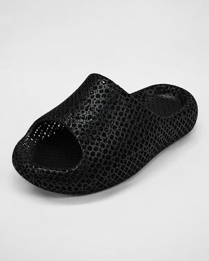 A single black open-toe slip-on clog-style shoe with a textured, perforated surface pattern, photographed on a light gray studio background.