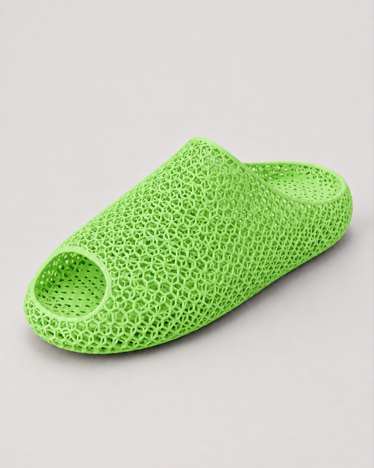 A bright lime green slip-on mule shoe with an open toe and a textured, honeycomb-like mesh upper, shown on a neutral light gray background.