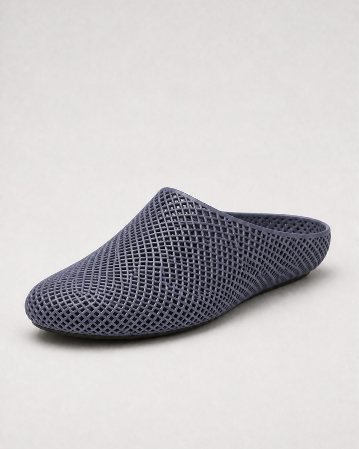 A single dark blue-gray mesh slip-on shoe with a textured honeycomb pattern, shown from a side profile on a light gray background.