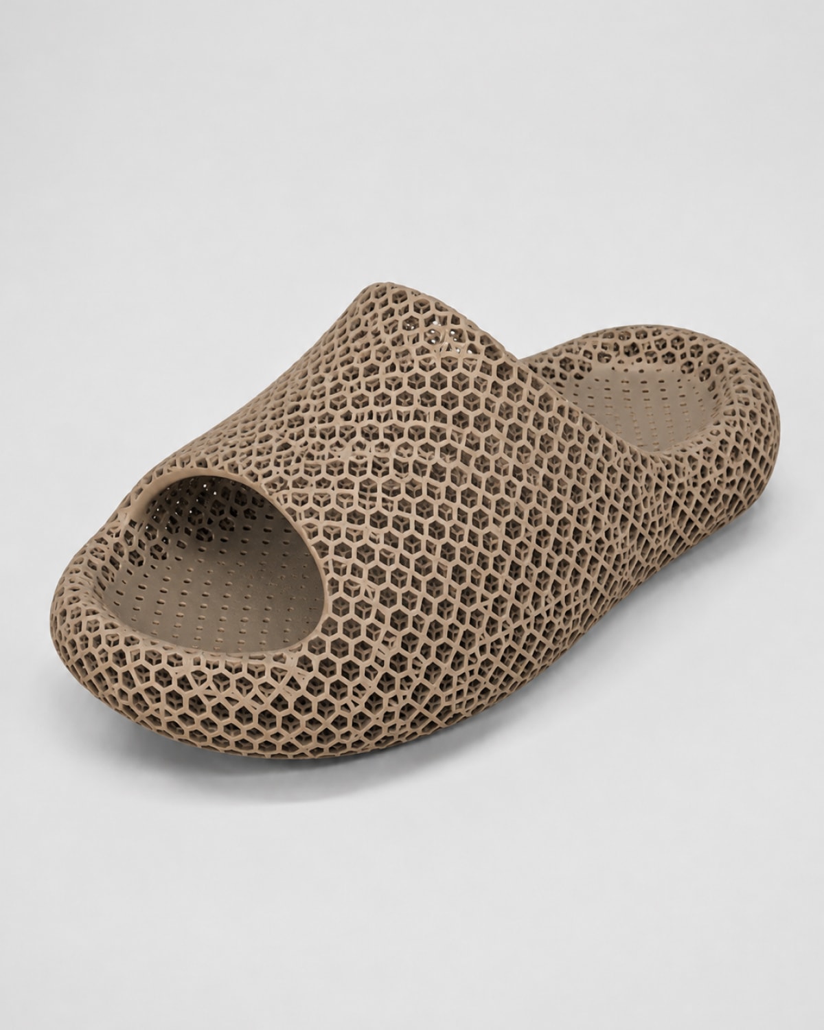 A single slip-on mule sandal with a distinctive honeycomb or perforated mesh texture, shown on a neutral light gray background.